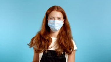 Koruyucu maskeli hoş bir kadın mavi arka planda 