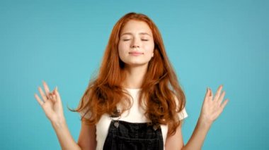 Sakin kız dinleniyor, meditasyon yapıyor. Kadın sakinleşir, derin derin nefes alır. Mavi stüdyo arka planında Mudra om. Yoga konsepti.