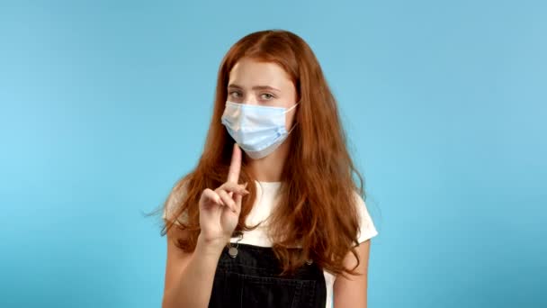 Tıbbi koruyucu maskeli güzel bir kız parmak izi olmadan onaylamıyor. Reddetmek, reddetmek, anlaşmazlık, mavi arka planda kadın portresi. — Stok video