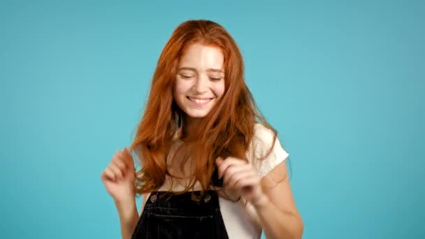 아름다운 머리를 가진 아름다운 여성이 푸른 스튜디오 배경에서 춤을 추고 있습니다. 귀여운 소녀 사진. 당, 행복, 자유, 젊음의 개념. — 비디오