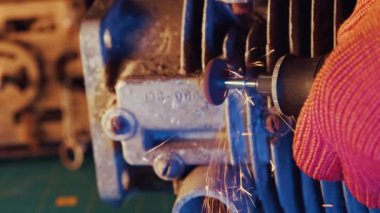 Araba motorunun metal sürgüsü el bilgisayarı ile gıcırdıyor. Ev otomobili tamiri kavramı, metalle çalışmak. Kıvılcımlarla yakın çekim.