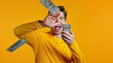 Şaşırmış mutlu yüzü olan adam, parayı boşa harcıyor. Amerikan para birimini aşan kişi. Stüdyonun arka planında dolarlar var. .