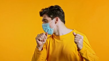 Steril maske takan mutlu Avrupalı adam, başarıya ulaştı, amaçlara. Sarı arka plandaki heyecanlı adam şaşırdı.