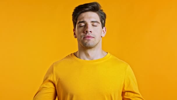 Homme calme, relaxant, méditant. Il se calme, respire profondément avec du mudra om sur fond de studio jaune. Concept de yoga. — Video