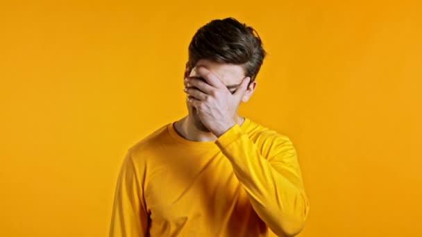 Frustrerad europeisk man gör ansikte palm gest över gul vägg bakgrund. Killen är trött, uttråkad av arbete eller studier, han besviken, hjälplös — Stockvideo