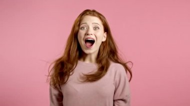 Kadın şaşkınlığı tasvir ediyor, zevkli bir yüz ifadesi sergiliyor. Şaşırmış, heyecanlı, mutlu kız. Pembe arka planda şok olmuş güzel bir kadın modeli..