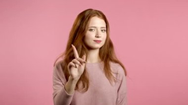 Parmak izi olmadan onaylamayan güzel bir kız, inkar jesti yapar. Reddetmek, reddetmek, anlaşmazlık, pembe arka planda kadın portresi.
