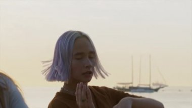 Menekşe boyalı saçlı, dans eden yetenekli ucube kadının portresi. Serbest stil hip-hop hareketleri yapan bir kız. Gün batımında okyanus ya da deniz kenarında açık hava eğitimi.
