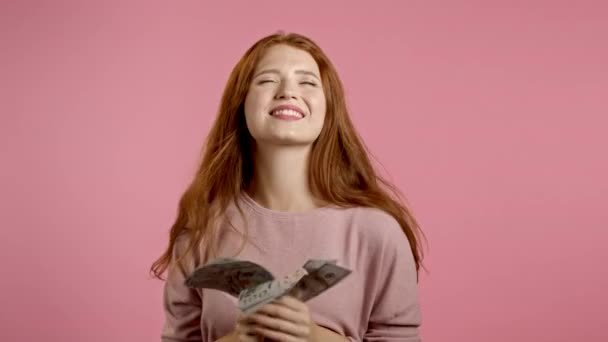 Erstaunt glücklich aufgeregte Frau zeigt Geld - US-Banknoten an rosa Wand. Mädchen, die Dollar verstreuen. Symbol für Erfolg, Gewinn, Sieg. — Stockvideo
