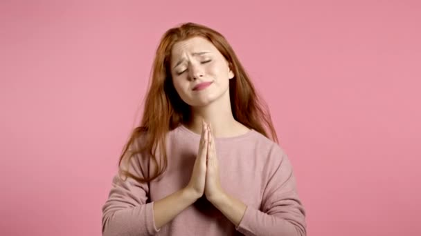 ピンクの背景で祈っている可愛い女の子。誰かが彼女の欲望を満たす懇願女,助け. — ストック動画