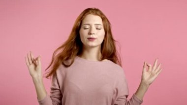 Sakin kız dinleniyor, meditasyon yapıyor. Kadın sakinleşir, pembe stüdyo arka planında derin derin nefes alır. Yoga konsepti.