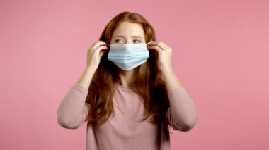 Genç ve güzel bir kadın koronavirüs salgını sırasında yüz maskesi takıyor. Pembe arka planda bir portre. COVID-19 salgınına karşı solunum cihazıyla koruma