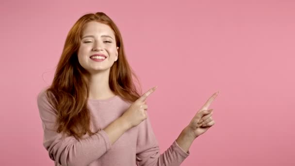 Копия космического портрета улыбающейся женщины указывает на то, что на левой стороне руки. Девушка представляет и показывает что-то изолированное на розовом фоне. — стоковое видео