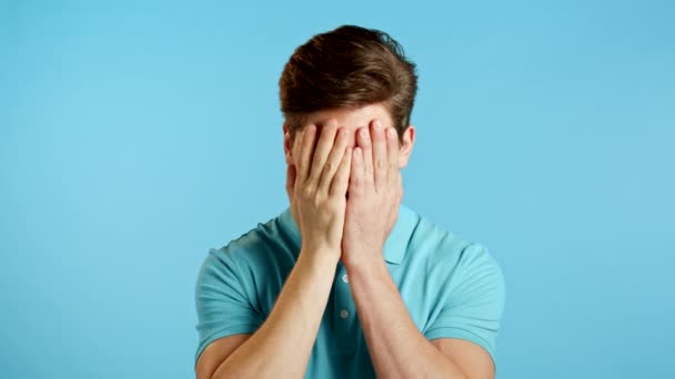 Jongeman bedekt zijn gezicht met handen van fatale teleurstelling, mislukking. Depressieve verloren man in t-shirt. Drama, emotie concept — Stockvideo