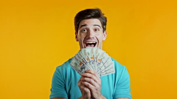 Homem animado feliz surpreendente mostrando dinheiro notas de dólares da moeda dos EUA na parede amarela. Símbolo de sucesso, ganho, vitória. — Vídeo de Stock