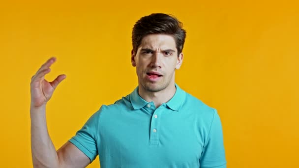 Handsome bored man showing bla-bla-bla gesture with hands and rolling eyes isolated on yellow background. Empty promises, blah concept. Lier. — Stock Video
