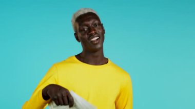 Heyecanlı mutlu Afrikalı adam mavi duvarda Amerikan doları banknotları gösteriyor. Başarı, kazanç, zafer sembolü.