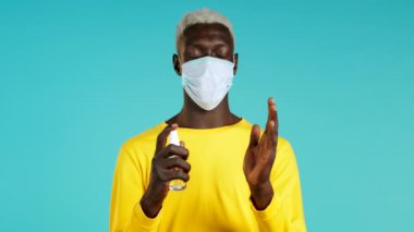 Koruyucu maskeli siyah adam ellerine antiseptik uyguluyor ve temiz ve steril olduğunu gösteriyor. Virüs konseptini durdur, bakteri koruması.