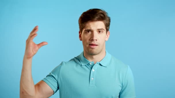 Schöner gelangweilter Mann mit bla-bla-bla-Geste mit Händen und rollenden Augen auf studioblauem Hintergrund. Leere Versprechungen, blabla Konzept. Lier. — Stockvideo
