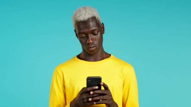Нахабний чорношкірий африканець отримує радісне повідомлення на мобільному телефоні. Парень не в себе с сюрпризом и радостью. Він виграв і радіє. Технологія, успіх, перемога, концепція щастя.. — стокове відео