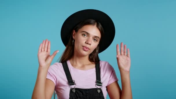 Hipster verveelde vrouw in hoed met bla-bla-bla gebaar met handen en rollende ogen geïsoleerd op studio blauwe achtergrond. Lege beloftes, blah concept. Lier. — Stockvideo