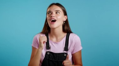 Mavi stüdyo arka planında enerjik ve aktif dans eden güzel bir kadın. Siyahlar içinde sevimli bir kız. Parti, mutluluk, özgürlük, gençlik kavramı.