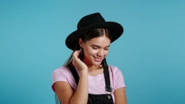 Çekici hippi, oyuncu, eskici ve şapkalı kadın gülümseyen, mavi duvar arka planında kameraya kur yapan. Güzel moda kızların portresi.