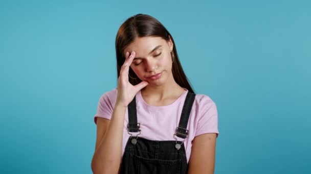 Dívka je unavená, znuděná prací nebo studiem, zklamaná, bezmocná. frustrovaný evropský žena přes modrý zeď pozadí. — Stock video