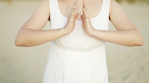 Mulher praticando ioga, namaste mudra gratidão sozinho na praia de areia na hora do pôr do sol verão. Menina de vestido branco. Religião, pureza, renúncia, conceito de espiritualidade. Movimento lento — Vídeo de Stock