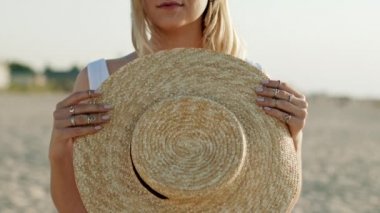 Boho çingene yüzüklü kadınların ellerini yakın, elinde saman şapkası var. Yazın kumsalda duran ve kayığını yuvarlayan bir kız.