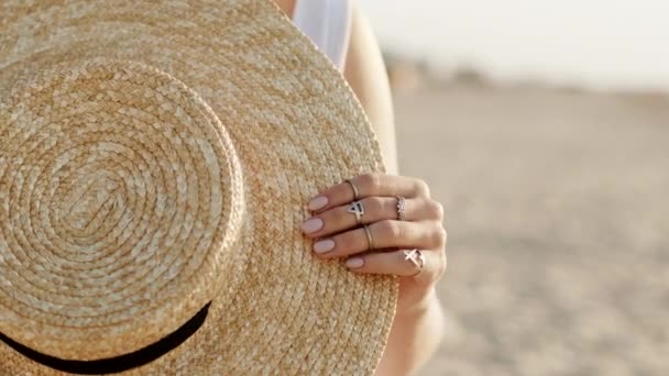 밀짚으로 유행하는 모자를 들고 있는 보호 집시들의 반지로 여성들의 손을 감싼다. 여름철에 해변의 모래사장에 서서 보트를 타고 있는 소녀 — 비디오