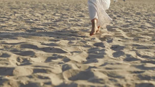 Beine von Mädchen in weißen langen Kleidern, die barfuß Sand am Strand oder in der Wüste laufen. Zeitlupe. Frau läuft vor Kamera — Stockvideo