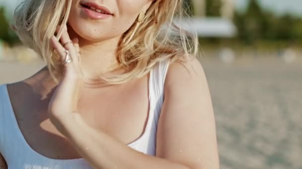 Sexig blond kvinna som står på stranden och rör vid vacker solbränd kropp. Lockande förföriskt porträtt av flicka med många ringar vidrör nyckelben. Långsamma rörelser. — Stockvideo