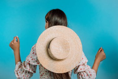 Mavi arka planda şapkası kameraya dönük dans eden tanınmayan bir kadın. Uzun saçlı kız. Parti, mutluluk, özgürlük, gençlik kavramı.