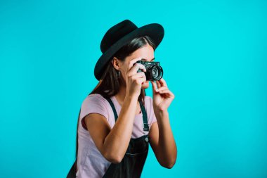 Genel olarak güzel bir kadın stüdyoda DSLR kamerasıyla fotoğraf çekiyor. Kız gülümsüyor ve fotoğrafçı olarak eğleniyor..