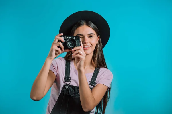 全体的に若いきれいな女性はスタジオで青の背景にデジタル一眼レフカメラで写真を撮ります.女の子は笑顔で写真家として楽しい. — ストック写真