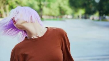 Genç dansçı kız hip-hop hareketlerinden hoşlanıyor. Menekşe boyalı saçlı modern kadın yaz aylarında kaykay parkında serbest dans gösterisi yapıyor. Yavaş çekim.
