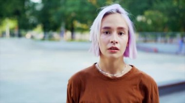 Genç dansçı kız hip-hop hareketlerinden hoşlanıyor. Menekşe boyalı saçlı modern kadın yaz aylarında kaykay parkında serbest dans gösterisi yapıyor. Yavaş çekim.