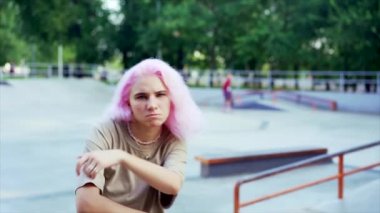 Genç dansçı kız hip-hop hareketlerinden hoşlanıyor. Pembe boyalı saçlı modern kadın yaz aylarında kaykay parkında serbest dans gösterisi yapıyor. Yavaş çekim.