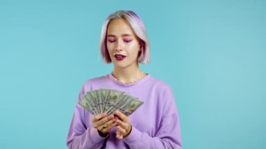Heyecanlı hippi kadın mavi duvarda Amerikan doları banknotları gösteriyor. Başarı, kazanç, zafer sembolü.