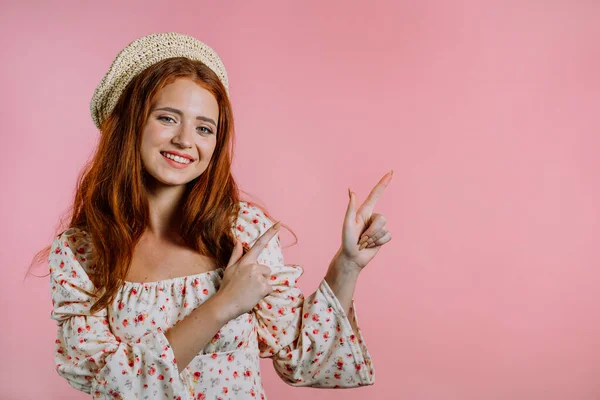 Felice donna sorridente che presenta e mostra qualcosa di isolato su sfondo rosa. Ritratto di ragazza, indica con le braccia a sinistra con spazio per copiare. — Foto Stock