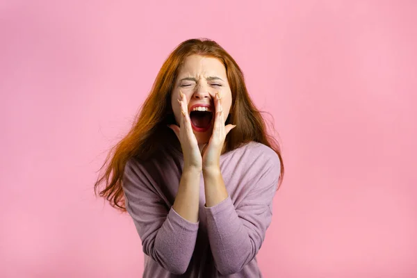 Frightened and screaming woman shocked isolated over pink background. Stressed and depressed pretty girl because of bad news.