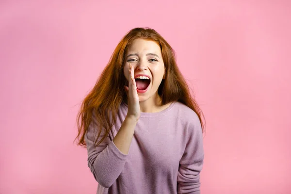 Frau mit roten Haaren sehr froh, sie schreit laut. Frau versucht, Aufmerksamkeit zu bekommen. Vertriebskonzept, profitables Angebot. Aufgeregt glücklich Dame auf rosa Studio Hintergrund. — Stockfoto