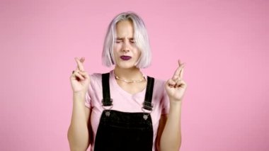 Mor boyalı saçları olan sevimli bir kız pembe arka plan için dua ediyor. Bir kadın birine arzularını tatmin etmesi için yalvarıyor..