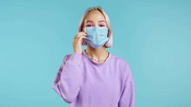 Potěšená žena si sundala ochrannou masku a hodila ji na podlahu jako symbol konce epidemie pandemie. Modré pozadí studia. — Stock video