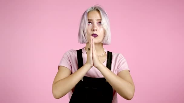 Carino ragazza con i capelli viola tinti pregare su sfondo rosa. Donna implorando qualcuno soddisfare i suoi desideri, aiutare con. — Video Stock