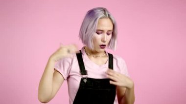 Kızın pembe stüdyo portresi, sıcaktan ya da boğuculuktan nefes veriyor, kollarını kendine sallıyor. Renkli mor saçlı genç, yorgun kadın tatminsiz ve mutsuz.. 