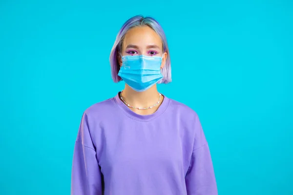 Joven chica adolescente bonita en la cara máscara médica durante la pandemia de coronavirus. Retrato sobre fondo azul. Protección con respirador contra brote de COVID-19 — Foto de Stock