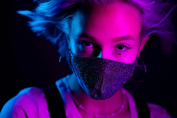 Mladá krásná módní žena v ochranné masce s drahokamy tančící v nočním klubu. Neonové barevné světlo. Detailní portrét módního modelu. — Stock fotografie