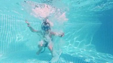 Mutlu küçük çocuk havuza dalıyor mavi berrak su, çocuklar için eğlence. Yaz yüzüşü, sualtı eğlencesi. Komik çocuk, dalmanın tadını çıkar. Aşırı açı. Yüksek kalite 4k görüntü